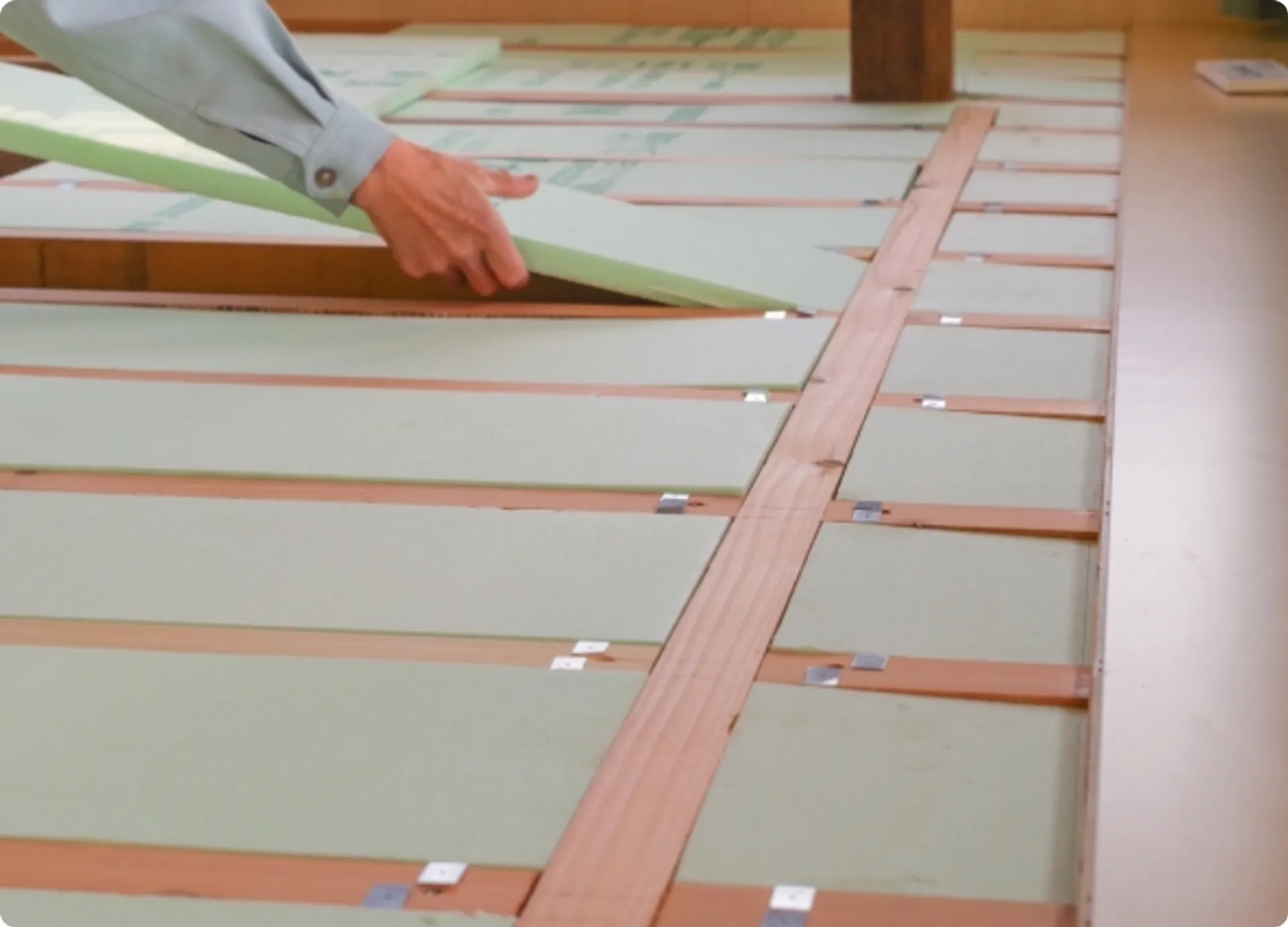 床下に断熱材を敷き詰めて冬の寒さ対策を行う施工風景