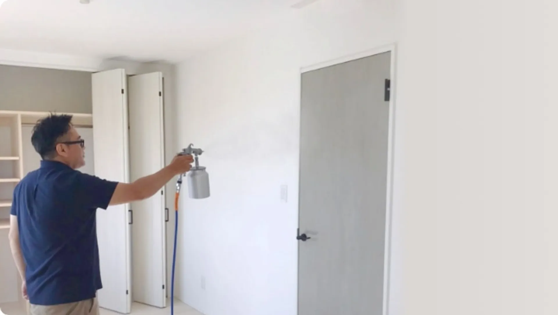 室内の壁にAIリキッド仕上げを吹きつけ施工している職人の様子